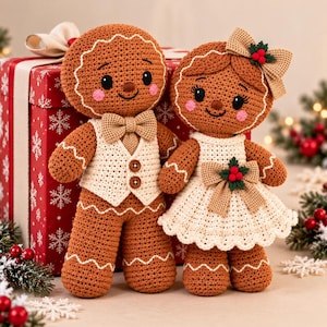 May include: Two crocheted gingerbread dolls with brown yarn bodies, white icing-style trim, and pink cheeks. One doll wears a beige vest with two brown buttons and a bow tie, while the other wears a beige dress with a bow and holly berry accent.