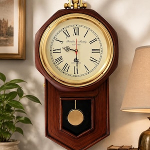 May include: A wall clock with a dark wood frame and a gold-toned circular bezel. The cream-colored face features black Roman numerals, black hands, a red second hand, and the text Franklin & Murphy EST 1868 OXFORD. A gold pendulum hangs below.
