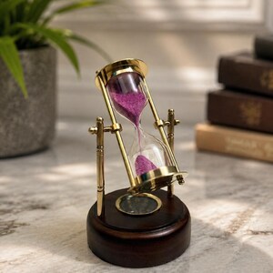 May include: A rotating hourglass with a polished brass frame and clear glass bulbs containing vibrant purple sand. The hourglass is mounted on a circular dark brown wooden base that features an integrated compass in the centre.