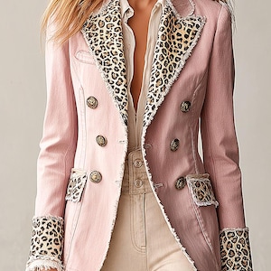 Puede incluir: Un blazer rosa claro de doble botonadura con estampado de leopardo en las solapas, las solapas de los bolsillos y los puños. La prenda tiene bordes deshilachados, botones metálicos dorados y un corte estructurado sobre una camisa blanca.