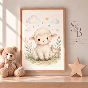Op de afbeelding: Een ingelijste print in aquarel-stijl met een pluizig wit lammetje dat in een grasveld met een houten hek zit, omringd door blauwe wolken en pastelkleurige sterren. De print bevat de tekst SmallBlossomStudio en Art Prints for a Brighter Home.