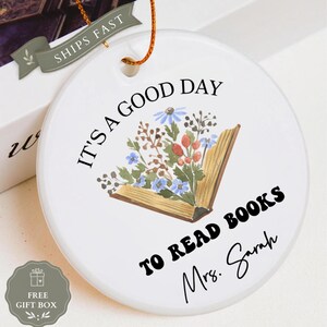 Ceramic ornament with floral book design, reads "It's a good day to read books Mrs. Sarah".