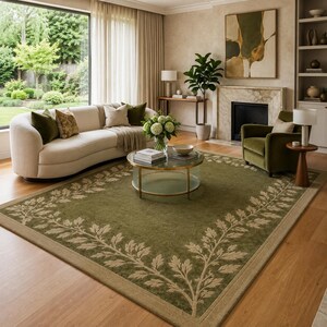 May include: A rectangular area rug featuring a deep olive green center field with a lighter beige border. The rug is decorated with a repeating botanical leaf vine pattern that frames the perimeter in a symmetrical, flowing design.