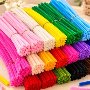May include: A collection of fuzzy pipe cleaners arranged in multiple bundles, each secured with a thin wire. The assortment features a vibrant spectrum of colors including pink, white, yellow, green, blue, red, orange, purple, black, and brown.