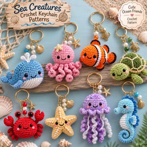 Könnte beinhalten: Eine Sammlung von acht gehäkelten Schlüsselanhängern in Form von Meerestieren, darunter ein blauer Wal, ein rosa Oktopus, ein orangefarbener Clownfisch, eine grüne Schildkröte, ein roter Krebs, ein gelber Seestern, eine lila Qualle und ein blaues Seepferdchen.