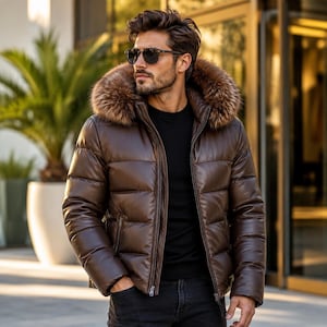 Könnte beinhalten: Eine dunkelbraune Steppjacke mit glatter Lederoptik, ausgestattet mit einer großen, dicken Kapuze mit braunem Kunstfellbesatz, einem Frontreißverschluss und horizontalen Steppnähten. Die Jacke wird über einem schlichten schwarzen Oberteil getragen.
