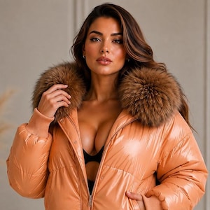 Può includere: Un piumino lucido color pesca caratterizzato da un ampio colletto in pelliccia sintetica marrone, maniche lunghe con polsini in maglia a coste e chiusura frontale con zip. La giacca presenta un design trapuntato sopra un capo nero con intagli.