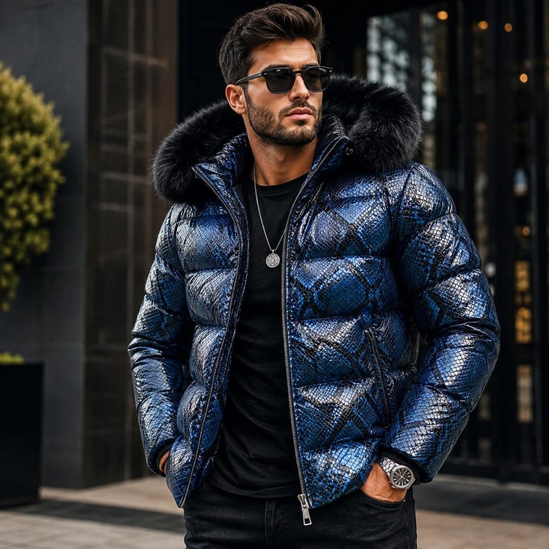 K&ouml;nnte beinhalten: Eine Daunenjacke mit gl&auml;nzendem blau-schwarzem Schlangenmuster, einer Kapuze mit schwarzem Fellbesatz, einem Frontrei&szlig;verschluss und langen &Auml;rmeln. Die Jacke wird &uuml;ber einem schlichten schwarzen T-Shirt getragen, kombiniert mit einer schwarzen Hose.