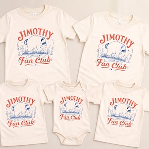 May include: A collection of five cream-colored garments including four short-sleeve t-shirts and one infant bodysuit. Each piece features a graphic of a raccoon with the red and blue text "JIMOTHY Fan Club" and "SEATTLE, WA" printed on the front.
