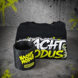 May include: A black t-shirt featuring the white and neon yellow text NACHT MODUS and a matching black cylindrical mug with a brick texture, the text NACHT MODUS in neon yellow, and a small yellow rectangular label reading SYSTEMFEHLER.
