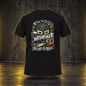 May include: A black t-shirt featuring a graphic print on the back. The design includes a Ferris wheel, a beer mug, and a pretzel, with the text "WIESNFEHLER" and "TOO LATE TO RESET" in white and yellow lettering against a dark, distressed background.