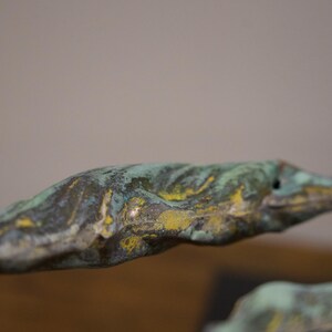 May include: Close-up of a green and yellow abstract sculpture with a textured surface.