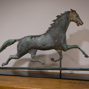 May include: A green metal horse sculpture with a long tail and mane, running on a black metal base. The horse is mounted on a long, thin metal rod.