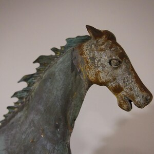 May include: A weathered bronze horse sculpture with a detailed mane and a textured finish. The horse's head is turned to the side, and its eyes are closed.