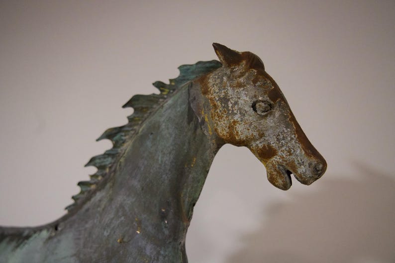 May include: A weathered bronze horse sculpture with a detailed mane and a textured finish. The horse's head is turned to the side, and its eyes are closed.