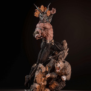 May include: A muscular figurine wearing a horned mask and black pants with gold trim, posed in a dynamic stance. The figure stands on a rocky base alongside a snarling panther, with a skull and a small drum-like object placed at the base of the rocks.