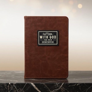 May include: A brown, textured, faux-leather devotional book with rounded corners. Centered on the front cover is a black rectangular label with white text that reads: One Minute WITH GOD FOR MEN 365 DAILY DEVOTIONS.