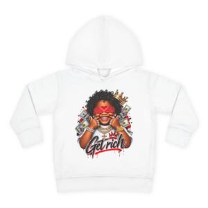 May include: A white hooded sweatshirt featuring a graphic print of a smiling person wearing a red bandana over their eyes, a gold crown, and gold jewelry. The design includes scattered dollar bills and the text Get Rich in a stylized black font.