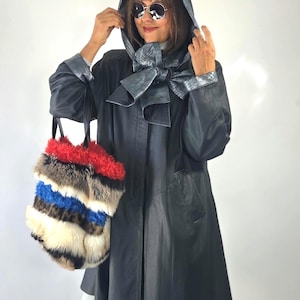May include: A dark charcoal hooded leather coat with a metallic silver-toned lining and a matching neck tie. A tote bag features horizontal stripes of red, brown, blue, and white faux fur with black leather handles and a structured base.