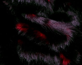 Puede incluir: Una tela de piel sintética de pelo largo y denso que presenta una base de color negro profundo con reflejos rojos vibrantes y saturados distribuidos por toda la textura. El material muestra una apariencia gruesa y peluda con hebras superpuestas.
