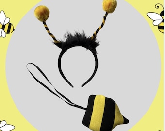 Könnte beinhalten: Ein schwarzer Haarreif mit zwei Antennen, gelben Pompons und schwarz-gelb gestreiften Stielen, akzentuiert durch schwarzes Kunstfell an der Basis. Dazu gehört ein gepolsterter Bienenschwanz mit horizontalen schwarz-gelben Streifen und einem schwarzen Gummiband.