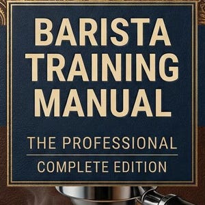 May include: A brown hardback book titled Barista Training Manual The Professional Complete Edition. The cover features gold embossed coffee plant illustrations, a portafilter dispensing espresso into a white cup, and coffee beans.