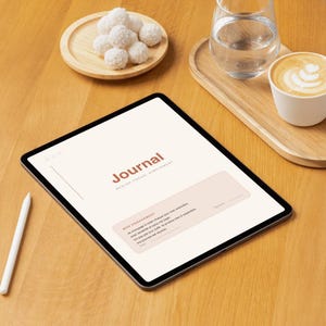 Peut inclure: Une tablette affichant une interface de journal numérique avec le texte Journal, Rester focus, simplement, et Mon engagement. L'écran présente un fond clair avec une zone de texte rose pâle. Un stylet blanc repose sur le côté gauche de la tablette.