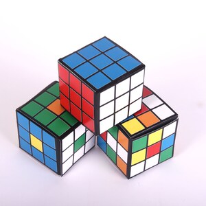 May include: Three colorful cube-shaped boxes with a black border and a pattern of squares in red, blue, green, yellow, and white.