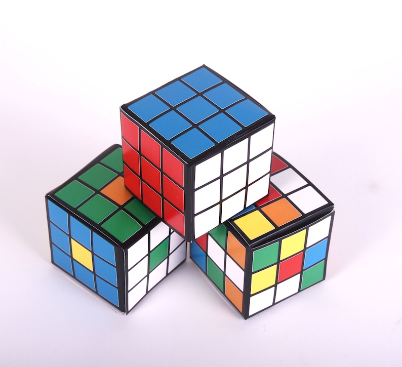 May include: Three colorful cube-shaped boxes with a black border and a pattern of squares in red, blue, green, yellow, and white.