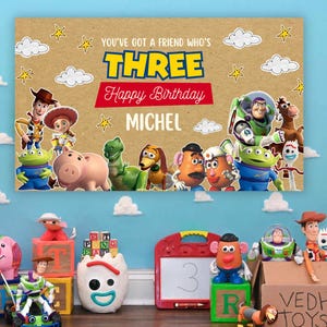 Könnte beinhalten: Ein rechteckiges Geburtstagsbanner mit einem Hintergrund in Kraftpapier-Optik und Toy Story-Figuren wie Woody, Buzz Lightyear und Jessie. Der Text lautet: YOU'VE GOT A FRIEND WHO'S THREE, Happy Birthday und der Name MICHEL in Weiß.