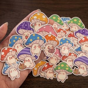 May include: A collection of die-cut stickers featuring anthropomorphic mushrooms with various colored caps, including red, blue, purple, yellow, and green. Each mushroom character has a smiling face and is depicted performing activities like reading.