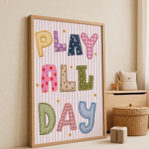 Peut inclure: Une affiche encadrée avec le texte PLAY ALL DAY écrit en lettres colorées à motifs rappelant du tissu. Le fond présente des rayures verticales rose clair et blanches, agrémentées de petites étoiles jaunes dispersées sur l'ensemble.