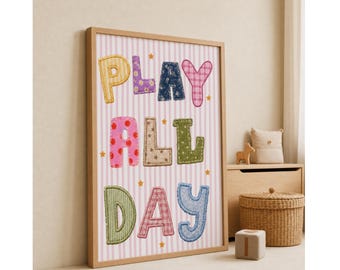 May include: A framed wall art print featuring the text PLAY ALL DAY in colourful, patterned, fabric-like letters. The background is a light pink and white vertical stripe pattern with small yellow stars scattered throughout the design.