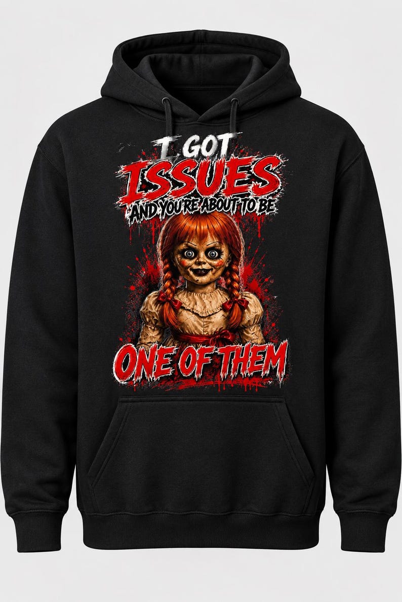 Puede incluir: Una sudadera con capucha negra que presenta un estampado gr&aacute;fico de una mu&ntilde;eca con trenzas rojas. El texto I GOT ISSUES AND YOU'RE ABOUT TO BE ONE OF THEM aparece en letras rojas y blancas, rodeado de salpicaduras rojas en el frente.