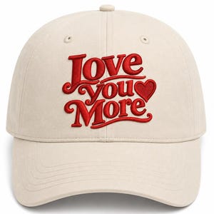 May include: A beige baseball cap featuring red embroidered text that reads Love you More with a small red heart icon at the end. The cap has a structured crown, a curved brim, and stitched eyelets on the top panels for ventilation and durability.