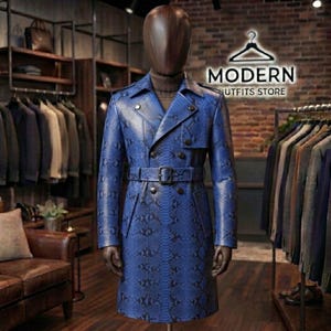 Könnte beinhalten: Ein zweireihiger Trenchcoat mit leuchtend blauem Schlangenledermuster, ausgestattet mit fallendem Revers, langen Ärmeln und einem passenden Gürtel mit rechteckiger Schnalle. Der Mantel hat eine strukturierte Silhouette mit dunklen Knöpfen.