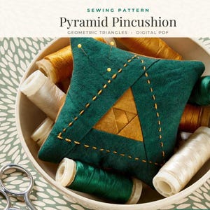 May include: A pyramid pincushion with dark green fabric and a central gold triangle, featuring yellow decorative stitching and two pins. The text reads SEWING PATTERN Pyramid Pincushion GEOMETRIC TRIANGLES DIGITAL PDF.