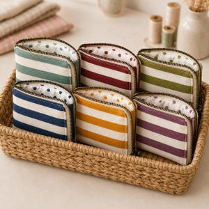 May include: Six small fabric zipper pouches arranged in a woven basket. Each pouch features horizontal stripes in blue, green, yellow, red, olive, or purple, paired with a white base. The interior lining of each pouch displays a matching polka dot pattern.