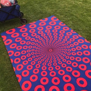 May include: A blue and red circular pattern picnic blanket. The blanket features a repeating pattern of red circles on a blue background.