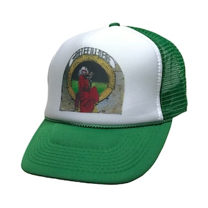 May include: Green and white trucker hat featuring the words "Grateful Dead" above an image of a figure in a red robe. The hat has a green brim and mesh back, with a white front panel.