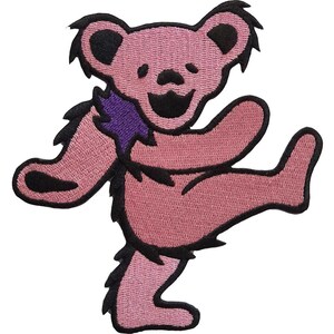 May include: Embroidered patch featuring a dancing pink bear with black outlines and a purple collar. The bear has a smiling face and is in a playful pose, with one leg raised. This patch is suitable for jackets, bags, or other fabric items.