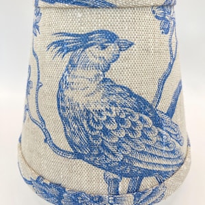 Peut inclure: Un abat-jour avec un motif d'oiseaux bleu et blanc. L'abat-jour est en tissu de lin et a un bord festonné.