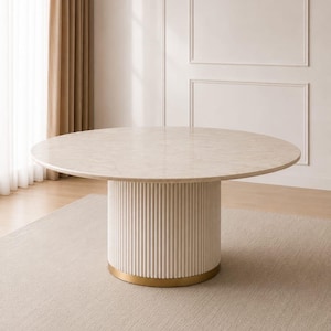 May include: A round dining table featuring a light beige marble-patterned top and a cylindrical base with vertical fluted detailing. The base is finished with a metallic gold-toned band at the bottom, providing a stable foundation for the table.