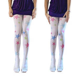 Peut inclure: Collants opaques blancs ornés d'un motif dispersé d'étoiles à cinq branches dans des tons rose, bleu clair et vert citron. Ces collants sont portés avec une mini-jupe violet foncé et des chaussures ouvertes claires, couvrant les jambes jusqu'aux pieds.