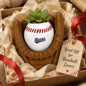 Peut inclure: Un pot de fleurs en forme de balle de baseball blanche avec des coutures rouges et le nom Lucas imprimé sur le devant, placé dans un gant de baseball marron. Une plante succulente verte est dans le pot, avec une étiquette beige Great Gift for Baseball Lovers.
