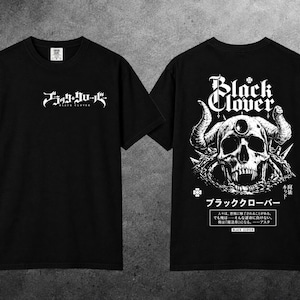 May include: A black short-sleeve t-shirt featuring a white graphic print. The front displays the Black Clover logo. The back features a large illustration of a horned skull with Japanese text, the Black Clover logo, and a quote box.