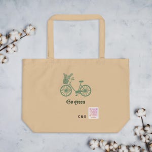 Może przedstawiać: Beżowa torba typu tote z zieloną grafiką przedstawiającą rower z koszem roślin. Pod rowerem znajduje się napis "Go green" ciemną czcionką, a obok litery "C & S" oraz mały kwadratowy kod QR z kolorowym wzorem.