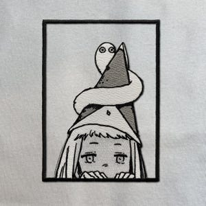 Peut inclure: Un écusson brodé rectangulaire présentant une illustration en noir et blanc au trait d'un personnage aux cheveux longs portant un chapeau pointu, avec une petite créature serpentiforme enroulée autour du sommet, le tout bordé de noir.