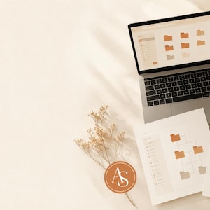 Peut inclure: Un ordinateur portable argenté affichant une interface de gestion de fichiers avec des icônes de dossiers orange, accompagné de deux documents imprimés avec des organigrammes, une petite plante en pot et un verre sur une surface claire.