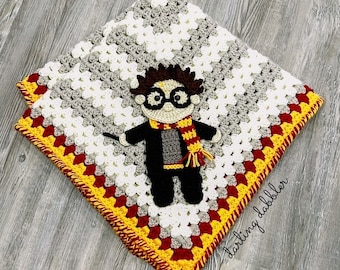 May include: A crocheted baby blanket with a Harry Potter character in the center. The blanket is made with white, gray, red, and yellow yarn. The border is a yellow and red crochet stitch. The text "darling dabbler" is in the bottom right corner.